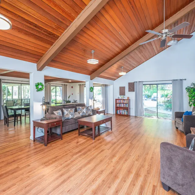 Spacious Living Room Design Bright and airy living room featuring wooden ceiling beams, large windows, and open layout with furniture including sofas and coffee tables.