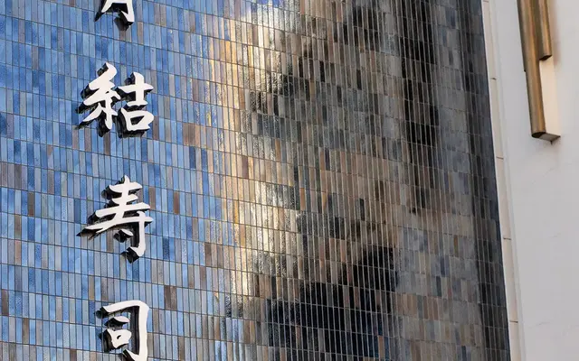 Exterior view of a sushi restaurant with reflective blue tiles and signage.