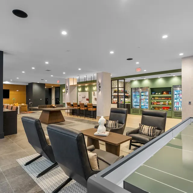 A spacious modern lounge area featuring tables, chairs, vending machines, and cozy seating arrangements.