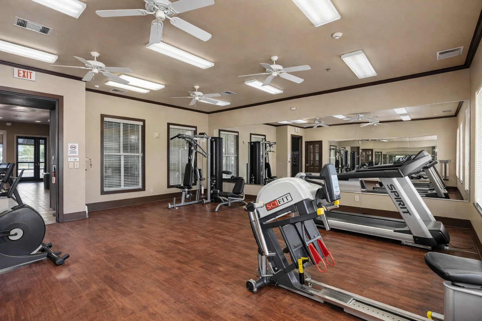 Interior view of a modern fitness center featuring exercise equipment and mirrors.