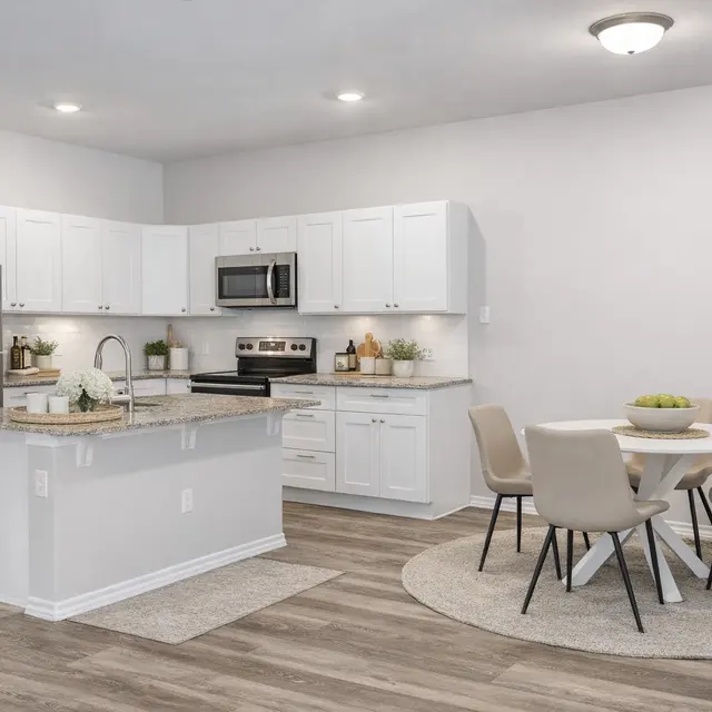 A modern kitchen featuring white cabinets, a stainless steel refrigerator, and granite countertops, with a dining table and chairs on the right side.