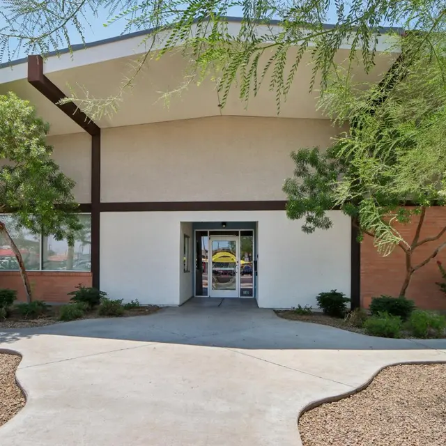 Modern Building Entrance Front view of a modern building with a wide entrance, surrounded by greenery and desert landscaping.