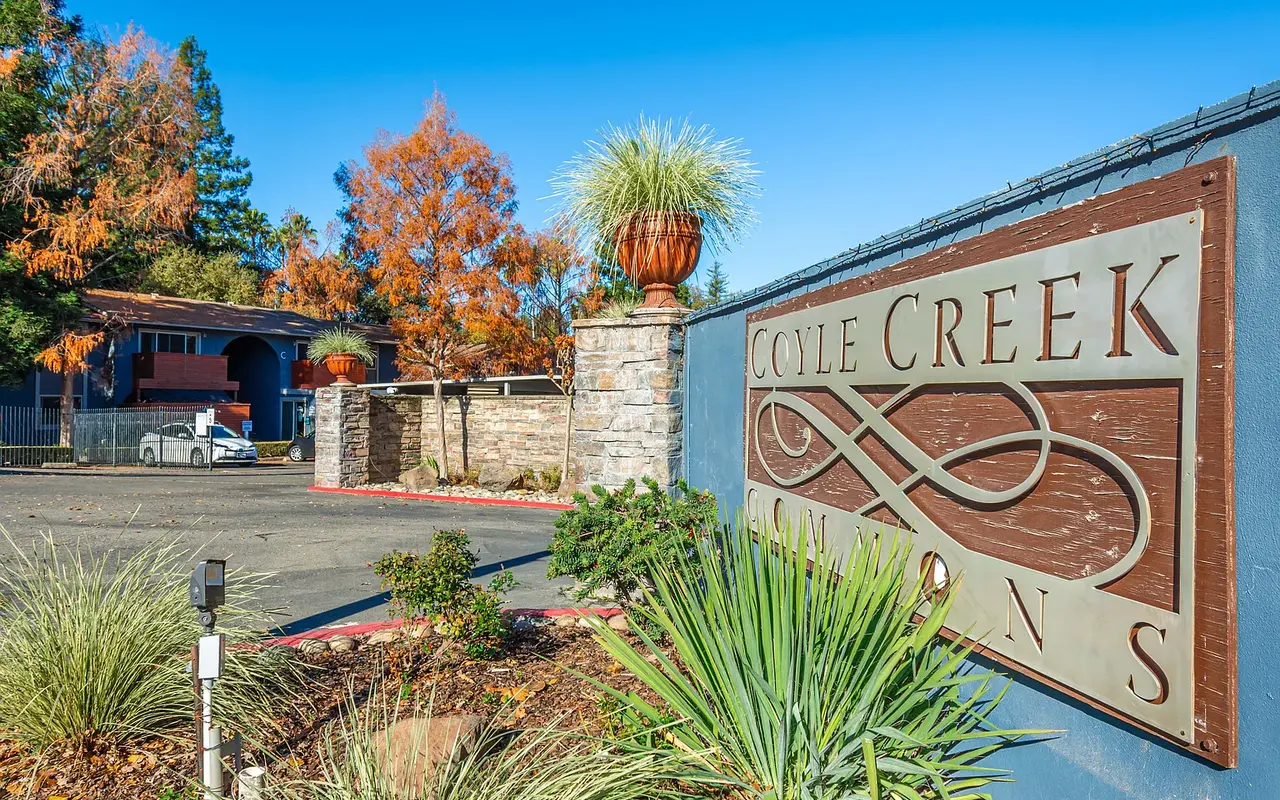 Entrance sign for Coyle Creek Canyons surrounded by green foliage and trees with autumn leaves