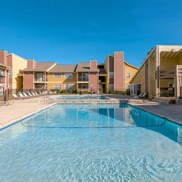 Outdoor swimming pool surrounded by lounge chairs and apartment buildings
