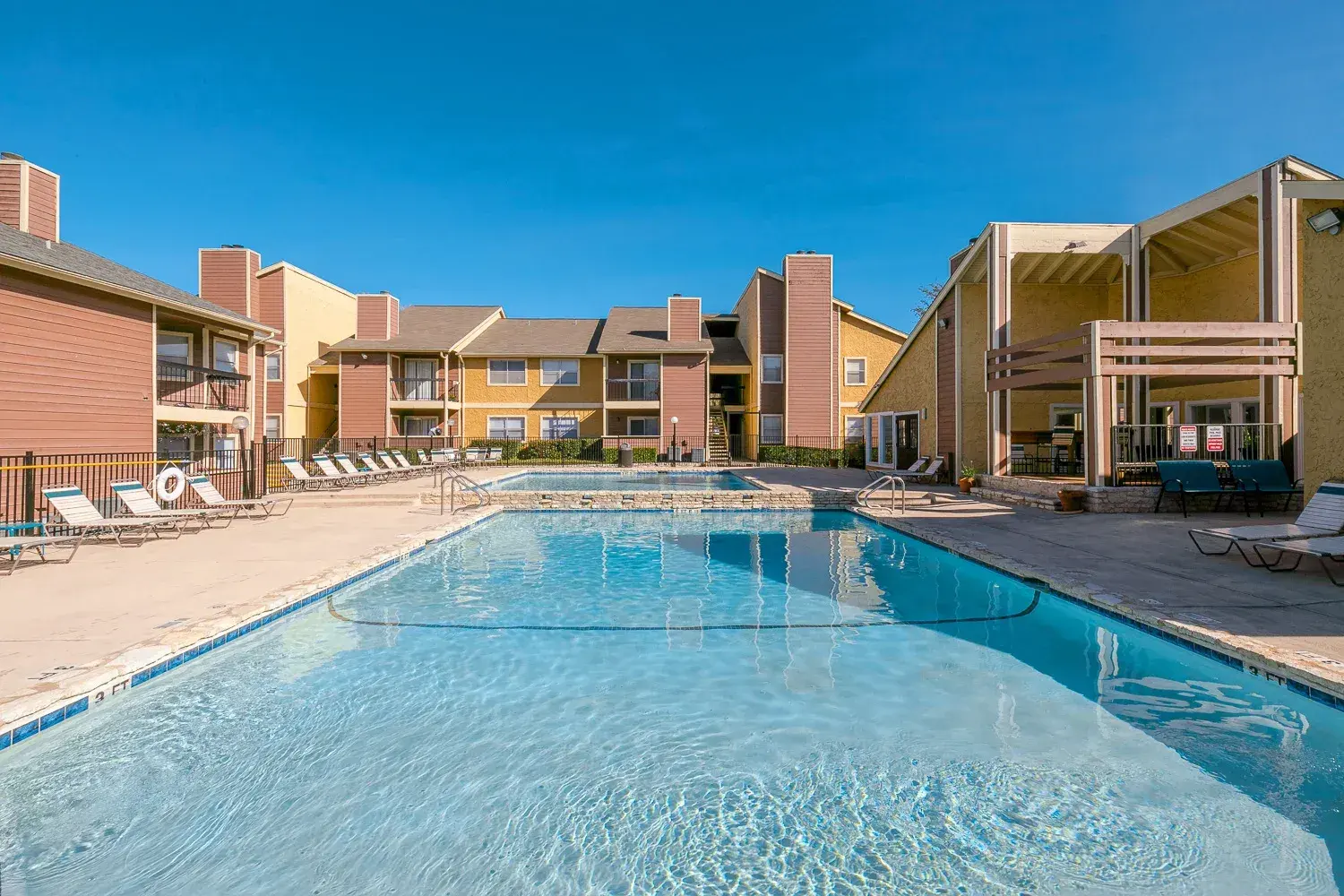 Outdoor swimming pool surrounded by lounge chairs and apartment buildings