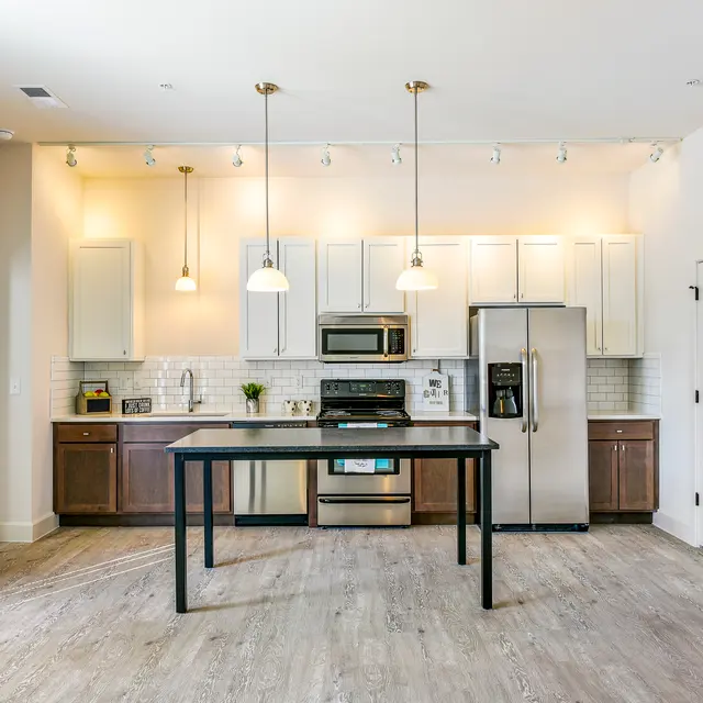 Modern Kitchen Interior A modern kitchen featuring an island with a stainless steel sink, stainless steel appliances, and white cabinets with warm wood tones.