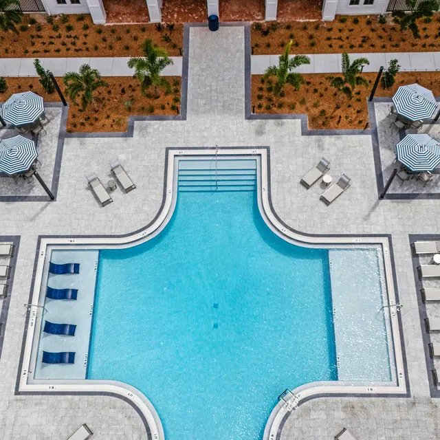 Aerial View of a Modern Pool Area Aerial view of a contemporary pool area surrounded by landscaped grounds and lounge chairs.