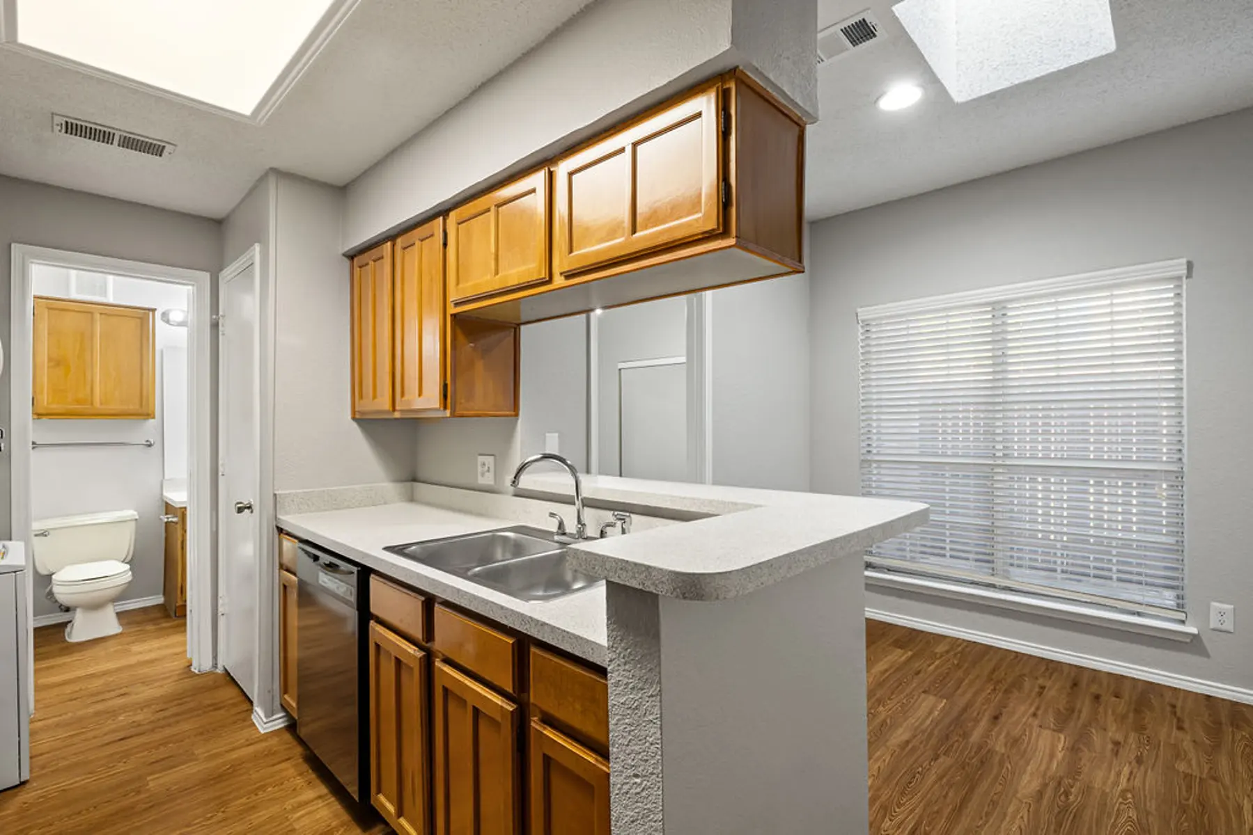 Modern Apartment Kitchen A modern kitchen featuring wooden cabinets, a sink, and an open layout leading to a living space with large windows.