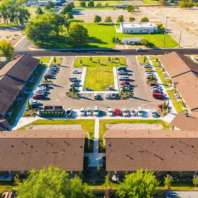 Aerial View of Apartment Complex Aerial view of an apartment complex featuring two rows of buildings surrounding a parking area and landscaped green space.