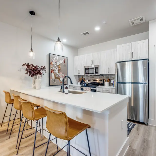 A modern kitchen featuring an island with bar stools, stainless steel appliances, and stylish cabinetry.