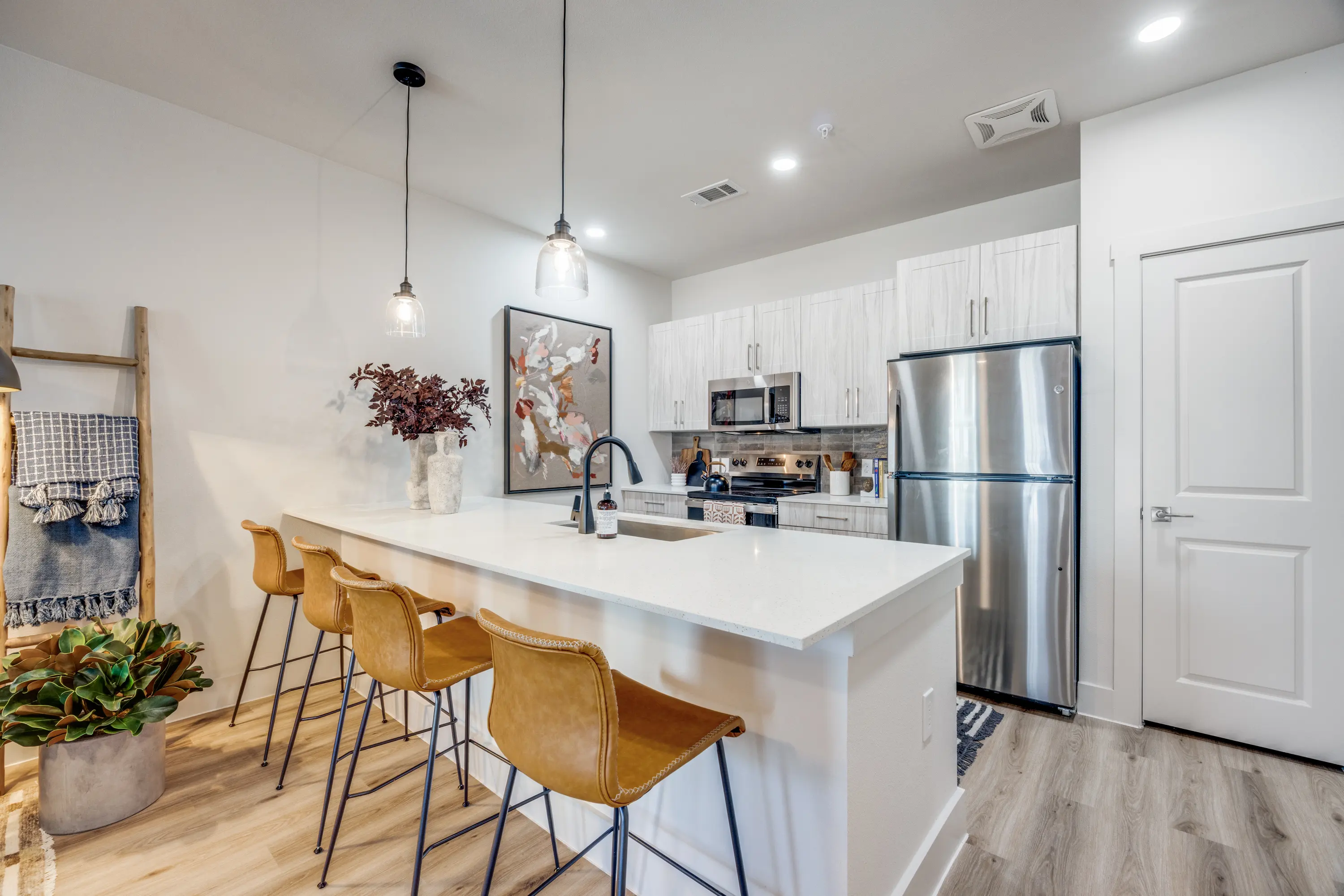 A modern kitchen featuring an island with bar stools, stainless steel appliances, and stylish cabinetry.