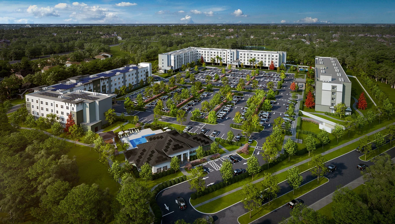 Aerial view of a modern residential complex with multiple buildings, parking lots, and lush greenery throughout the area.