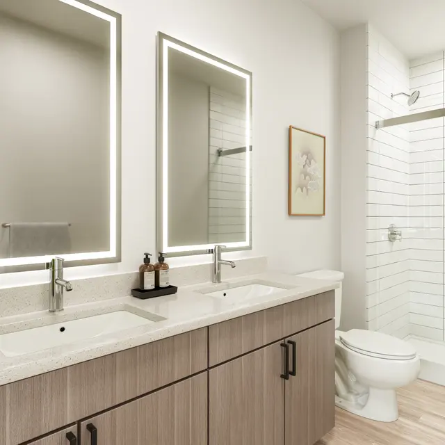 A modern bathroom featuring dual sinks with sleek fixtures, backlit mirrors, a shower area with white tiled walls, and wooden flooring.