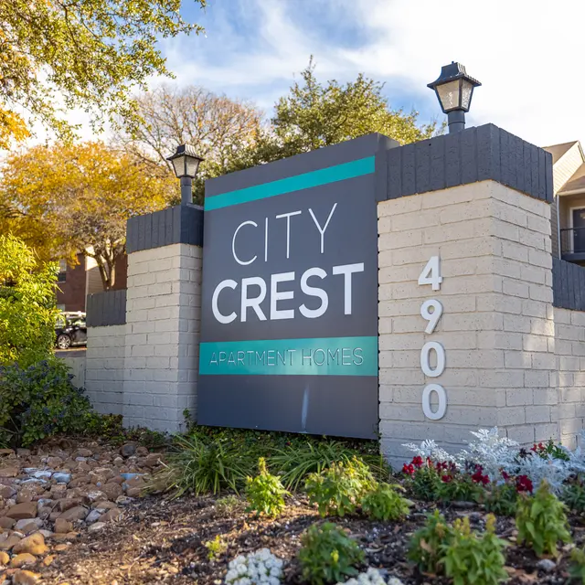 Signage for City Crest Apartments, featuring the name and address, surrounded by landscaping with flowers and decorative stones.