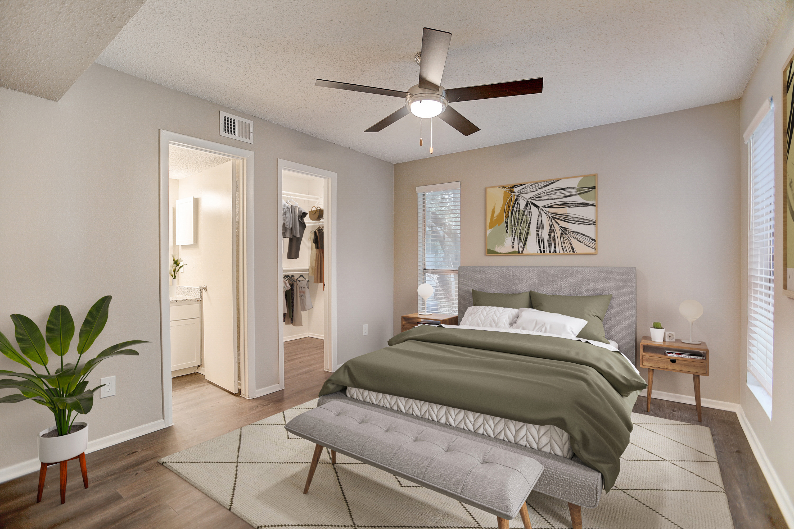 Modern Bedroom Interior A well-decorated bedroom featuring a gray bed with green bedding, a bench at the foot of the bed, a plant in a planter, and a bright wall with a nature-themed painting. The room has a ceiling fan and a visible doorway leading to a bathroom.