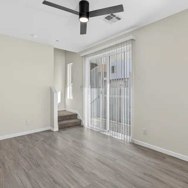 Interior view of a modern living room with a ceiling fan and sliding glass door.