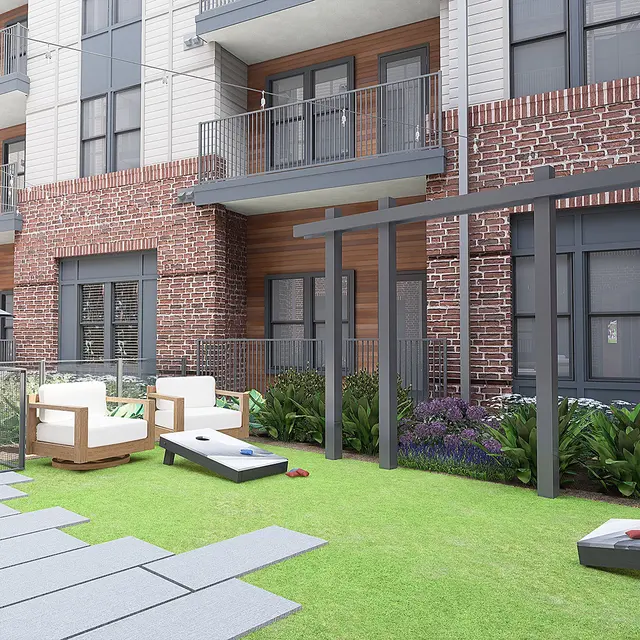 An outdoor area of an apartment complex featuring lounge chairs, umbrellas, and a landscaped garden with green grass and decorative plants.