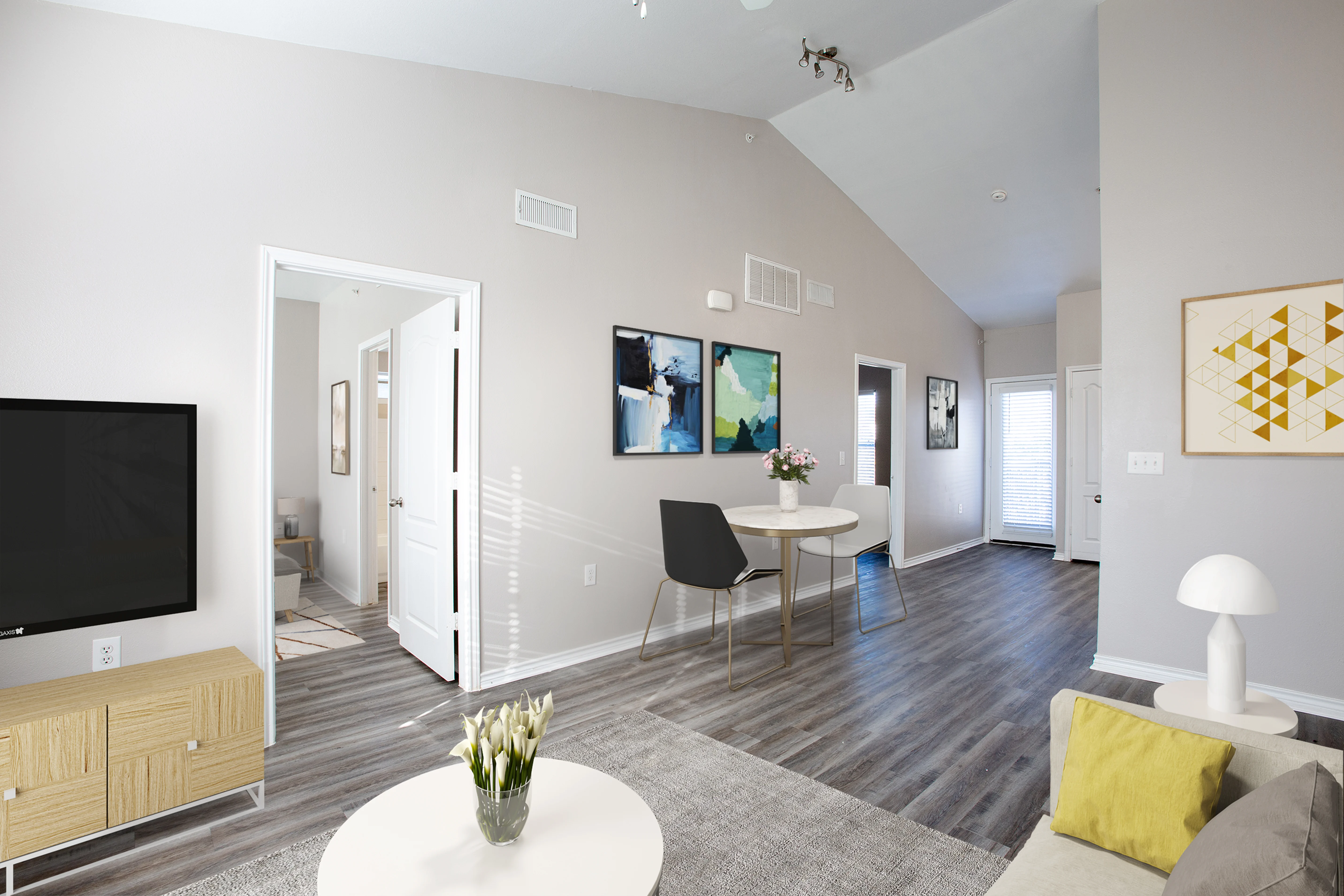 Modern Living Room Interior A contemporary living room featuring a television on a cabinet, modern artwork on the walls, and a cozy seating area with a table and decorative flowers.