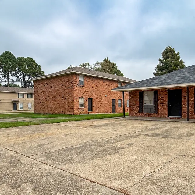 View of an apartment complex with brick buildings and open parking area.