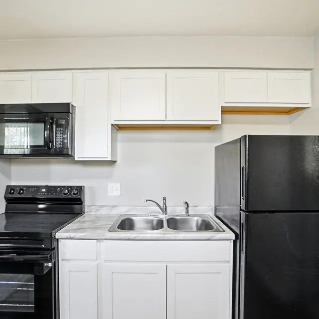 Modern kitchen featuring black appliances, white cabinetry, and a double sink.