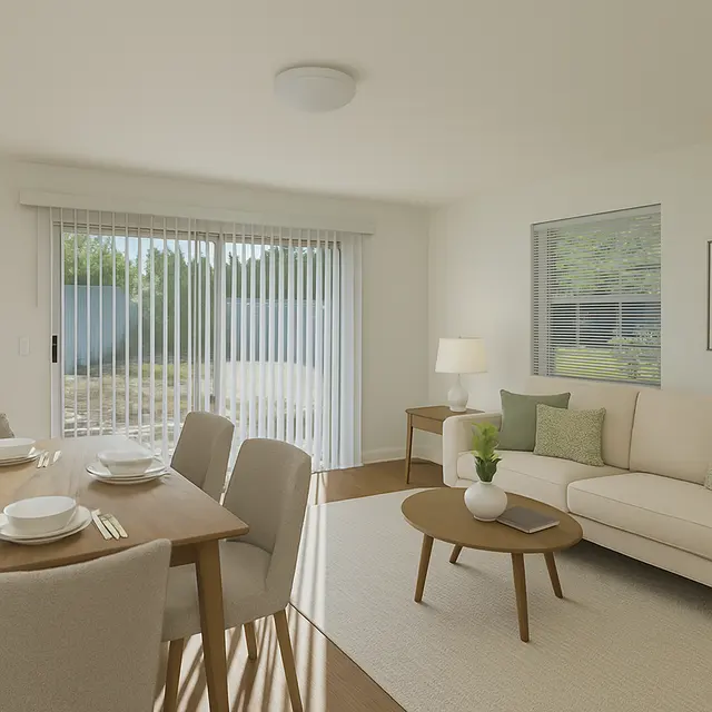 Contemporary Living Room Interior A modern living room featuring a comfortable light couch, wooden dining table set for four, and large sliding glass doors with sheer curtains letting in natural light. There's a side table with a lamp and a plant on the couch.