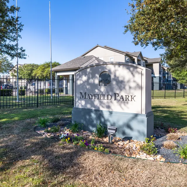 Sign at the entrance of Mayfield Park, surrounded by landscaping and trees.