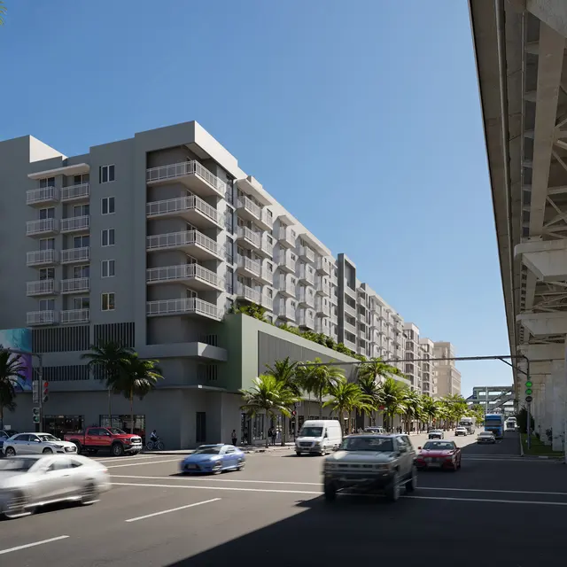 A modern apartment building featuring multiple balconies, situated alongside a busy street with cars and palm trees under a clear blue sky.