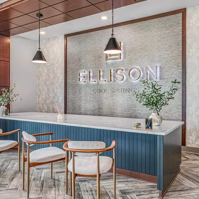 Modern reception area with a sleek counter and stylish seating, featuring the name 'ELLISON' in illuminated letters on the wall.