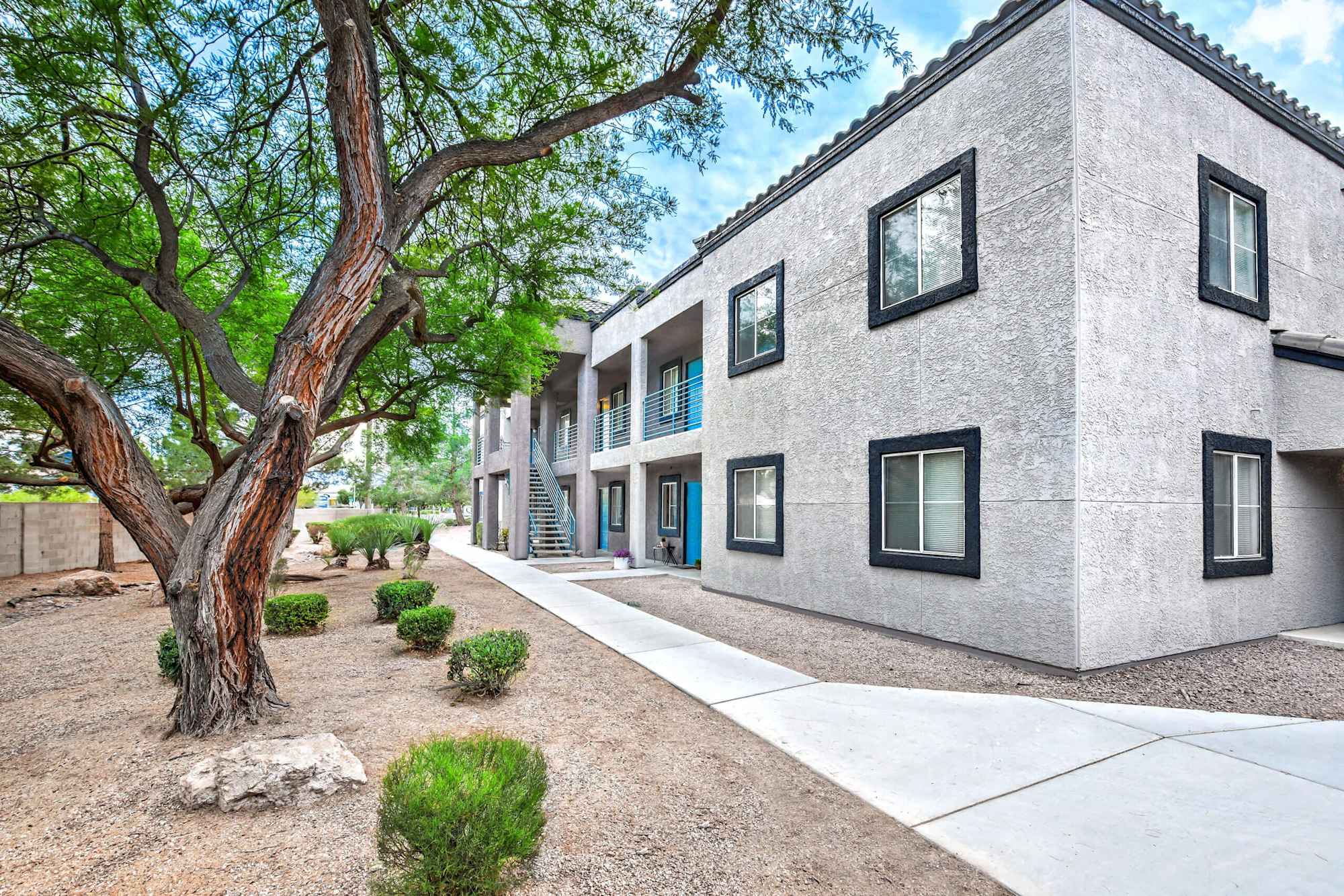 Exterior view of a modern apartment building surrounded by landscaped pathways and greenery.