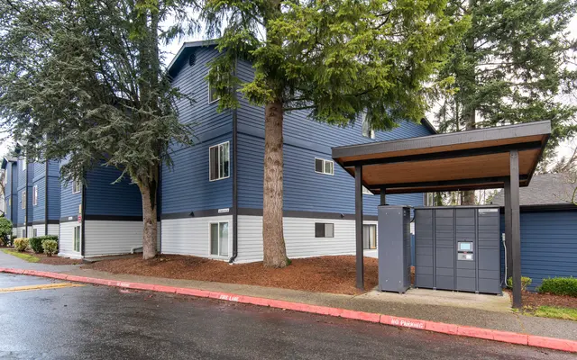 Exterior view of a modern blue apartment complex surrounded by trees