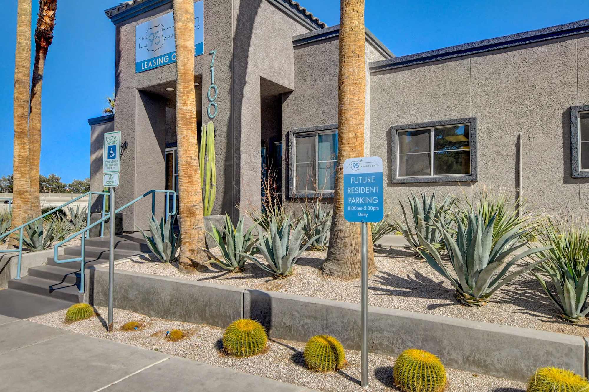 Exterior view of a leasing center with palm trees and desert landscaping.
