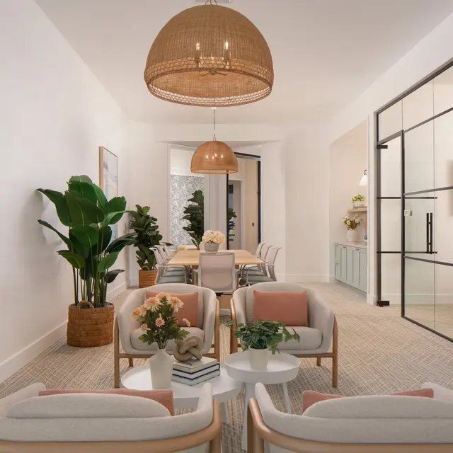 A modern interior living space featuring a light color palette, comfortable seating, plants, and a dining area at the back.