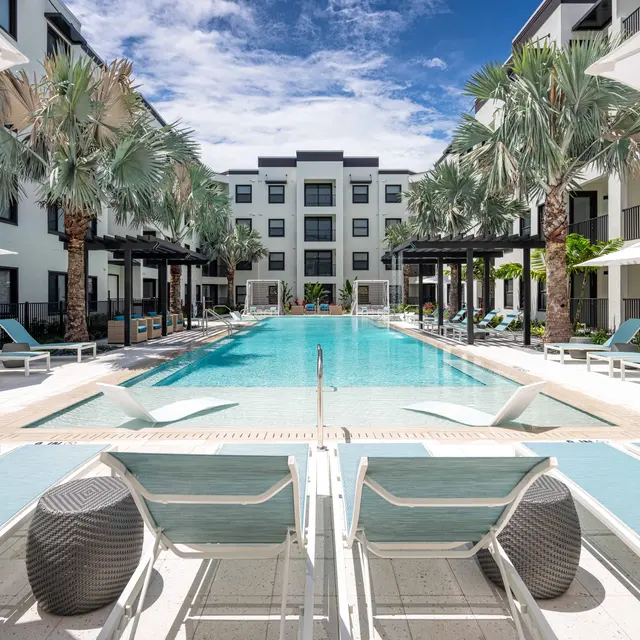 Modern pool area surrounded by palm trees and lounge chairs
