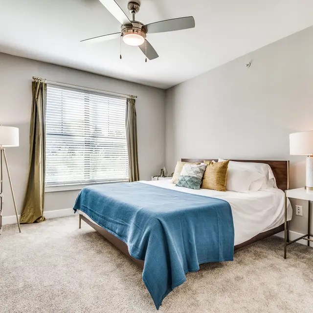 Centreport Lake Furnished bedroom with a large window for natural lighting and a ceiling fan with lights on carpeted floors.