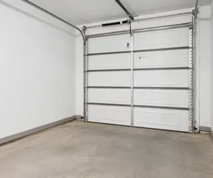 Empty Garage Interior An empty garage space with a gray concrete floor and a white garage door.