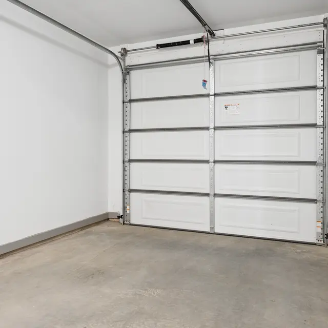 Empty Garage Interior An empty garage space with a gray concrete floor and a white garage door.