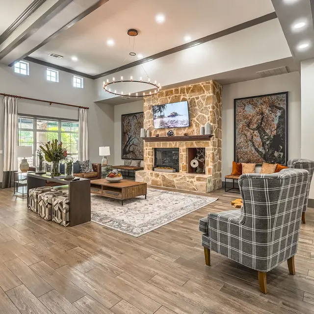 A modern living room with a stone fireplace, large windows, and stylish decor.