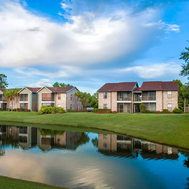 Modern Venice, FL apartments overlooking a pond surrounded by grass.