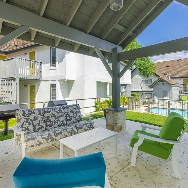 Outdoor seating with cushioned patio seated area under covered area by the resident pool