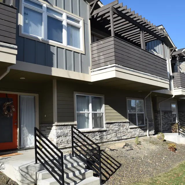 Modern Apartment Building Exterior Exterior view of a modern apartment building featuring balconies, stone details, and a red front door.