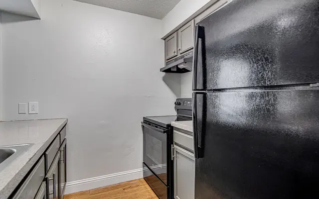 Kitchen with black appliances, grey cabinets, and wood floors