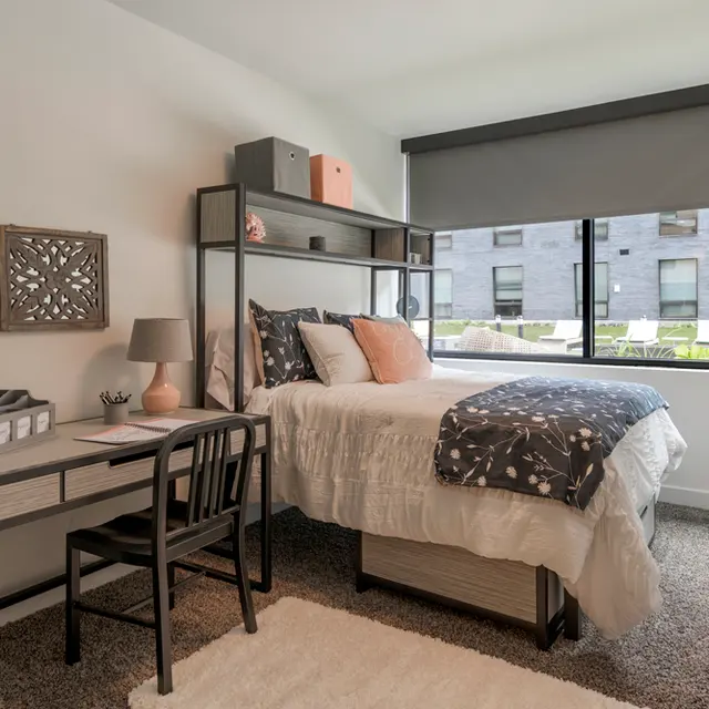 Two-Bedroom Student Apartments in Syracuse, NY - 505 on Walnut - Bedroom with Carpeting, Bed, Study Desk and Chair, and Expansive Window.

