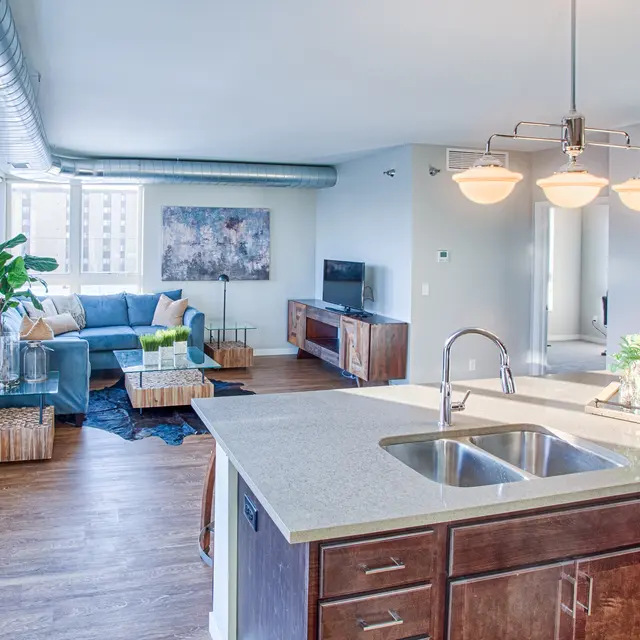 Open-concept apartment at Woodrow in Fargo featuring large windows, exposed ductwork, and stylish furniture