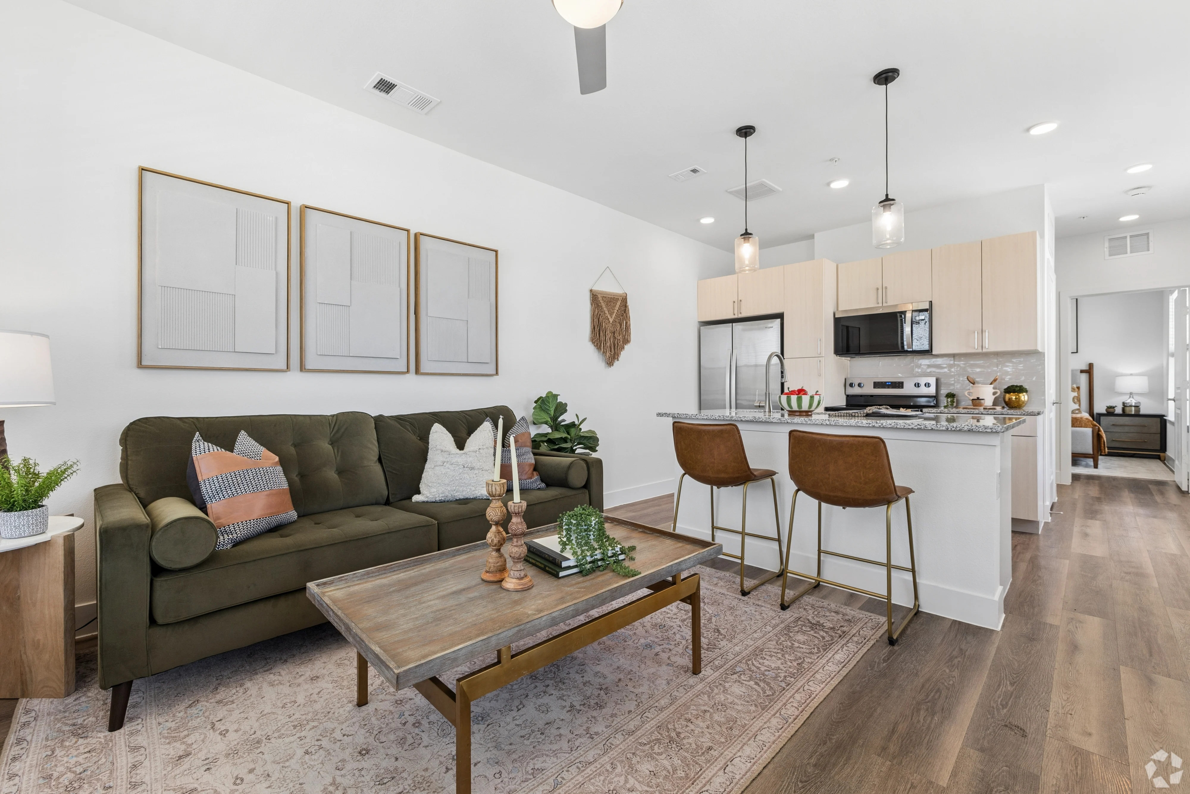 Stylish Modern Living Room A modern living area featuring a green sofa, wooden coffee table, pendant lights, and an open kitchen in the background.