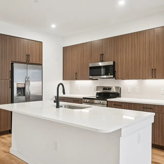 A contemporary kitchen featuring a center island, stainless steel appliances, and wood cabinetry.