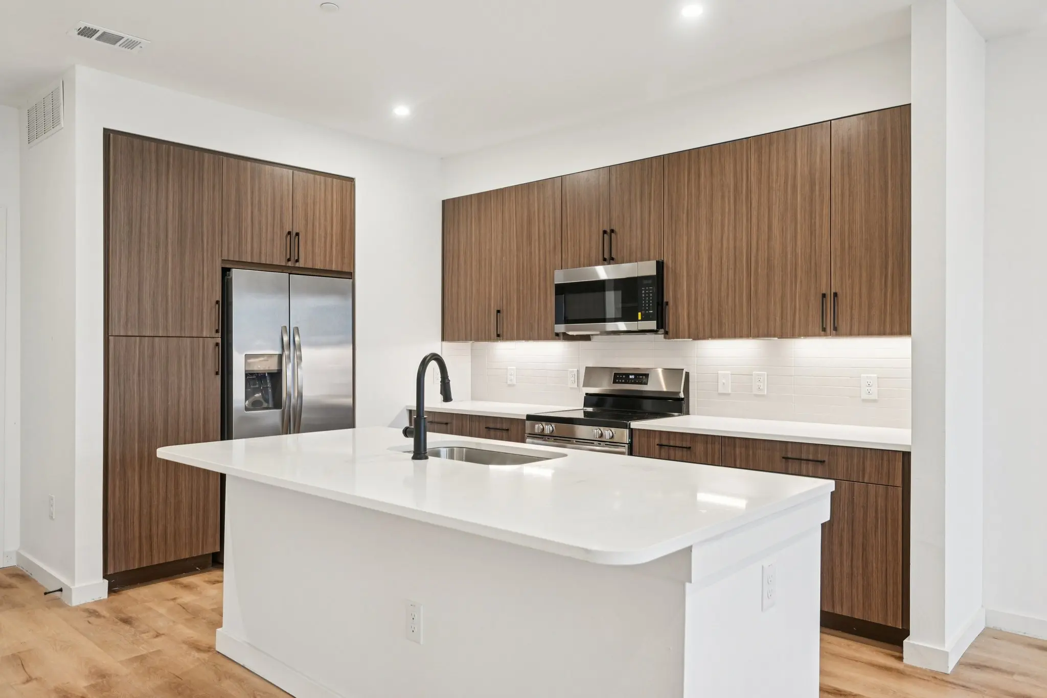 A contemporary kitchen featuring a center island, stainless steel appliances, and wood cabinetry.