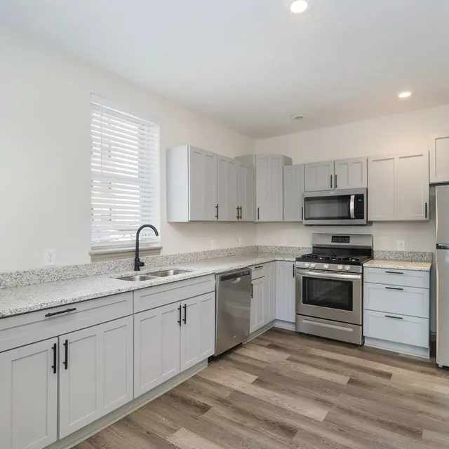 A modern kitchen featuring light gray cabinets, a stainless steel appliance set, and granite countertops.