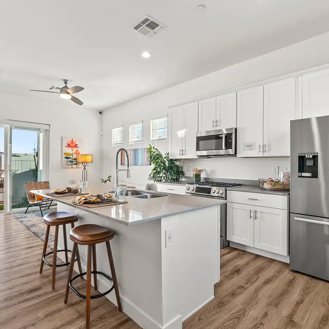 Contemporary Kitchen Design A contemporary kitchen featuring white cabinets, stainless steel appliances, a large kitchen island with bar stools, and an open layout leading to a dining area.