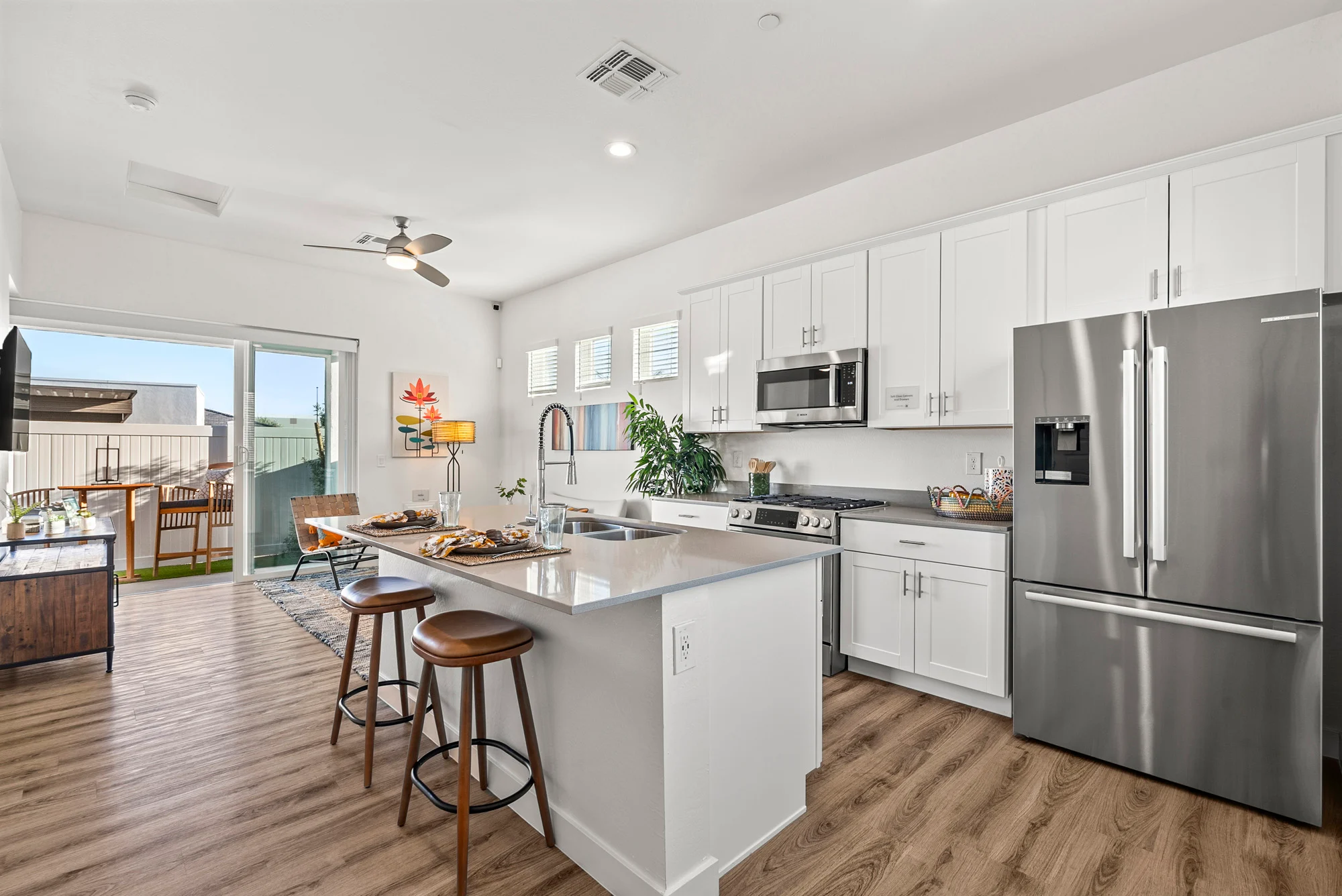 Contemporary Kitchen Design A contemporary kitchen featuring white cabinets, stainless steel appliances, a large kitchen island with bar stools, and an open layout leading to a dining area.