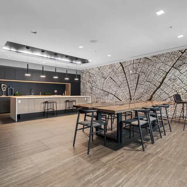 Modern Kitchen and Dining Area A modern kitchen and dining area featuring a large wooden table with black chairs, a sleek kitchen with dark cabinetry, and a decorative wall depicting a city map.